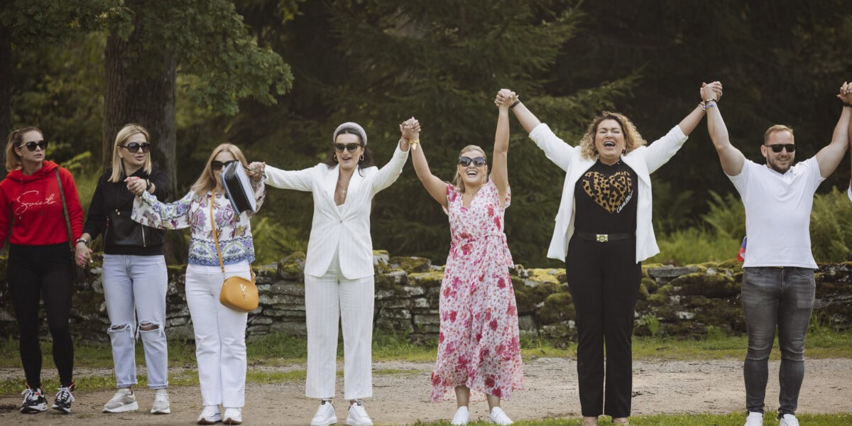 Inimesed on ringis ja hoiavad käest kinni, et tekitada ühistunnetust ettevõtte suvepäevadel