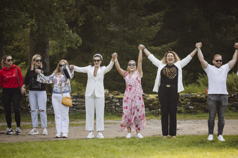 Inimesed on ringis ja hoiavad käest kinni, et tekitada ühistunnetust ettevõtte suvepäevadel