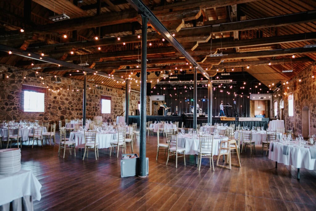 Pildil on Mooste mõisa folgikoda peosaal ümmarguste laudadega, mille ümber on toolid.