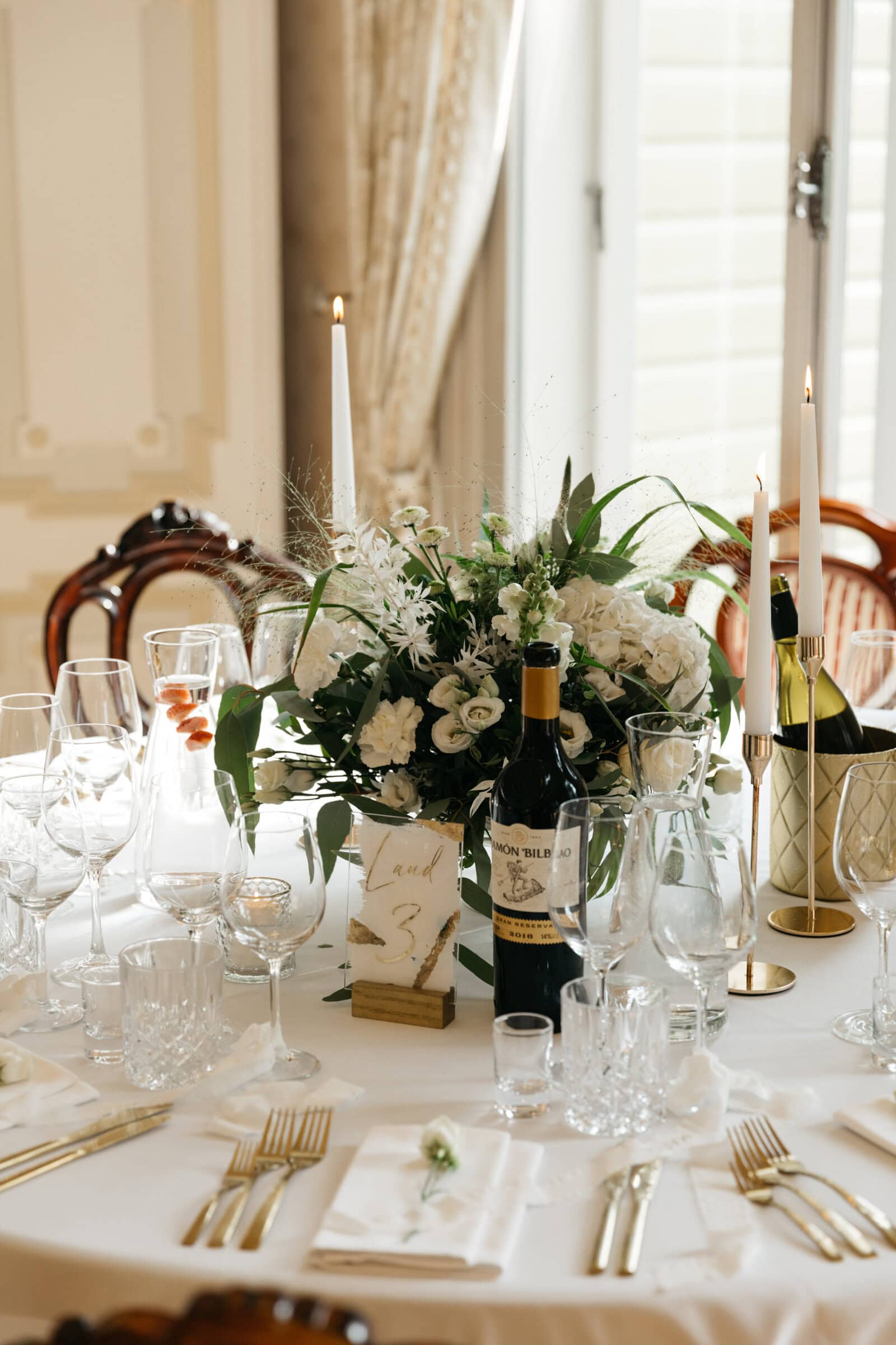 Pildil on pulmalaud koos klaaside, lauasildi ja lilleseadega