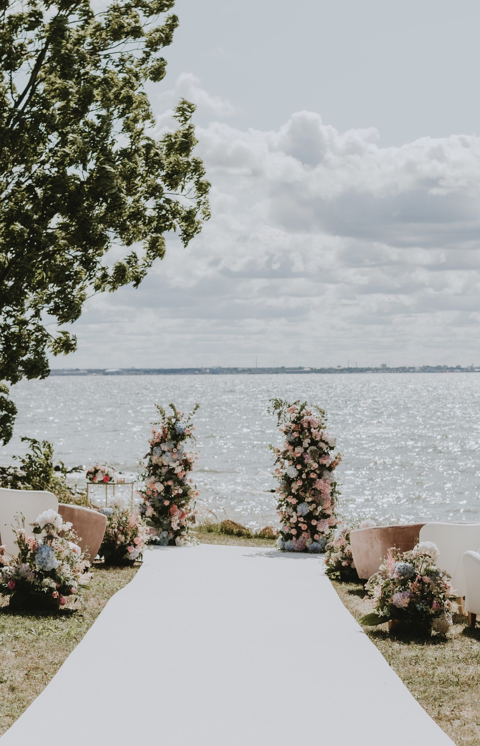 Pildil on värviliste lilledega tseremooniakaar, mille taustal on vaade merele